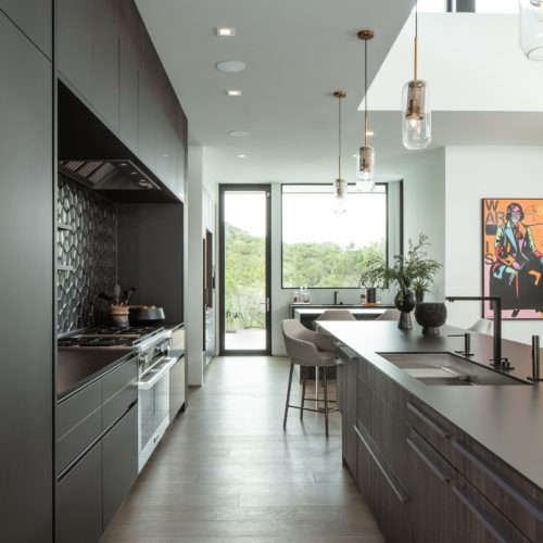 alt="interior kitchen view of island with elm paneling on drawers with gray griprail handles and cabinets in carbon gray matte satin lacquer"