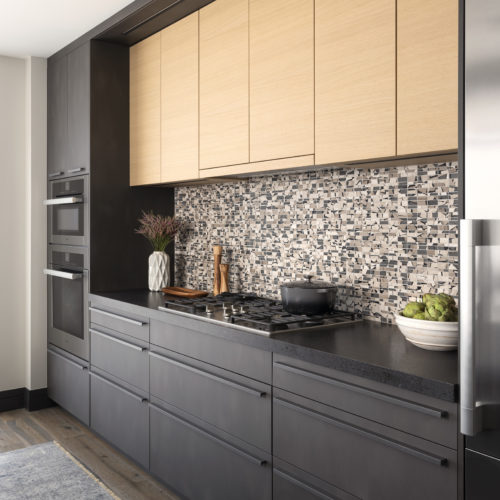 alt="dark gray minera steel effect kitchen lower cabinets with glimmer strip handle and natural oak uppers"